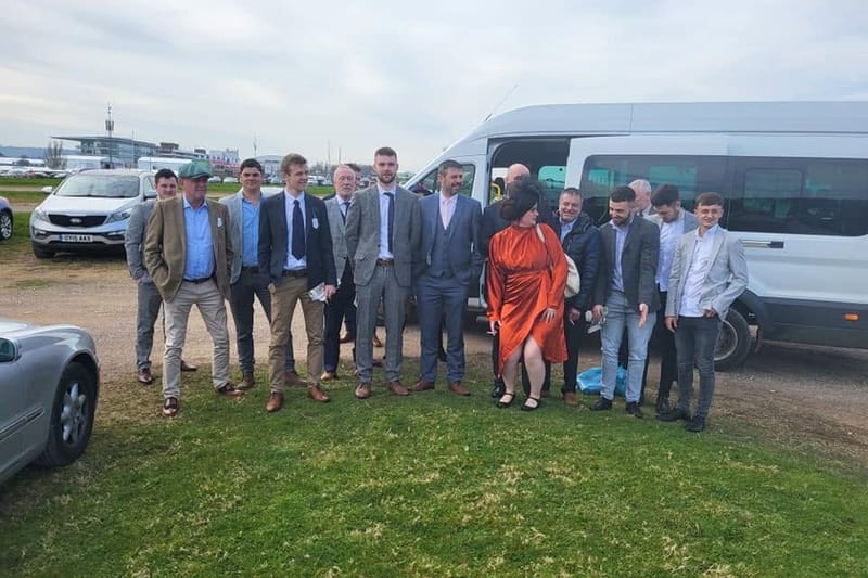 A race-day party in suits standing beside a Mawley Minibus